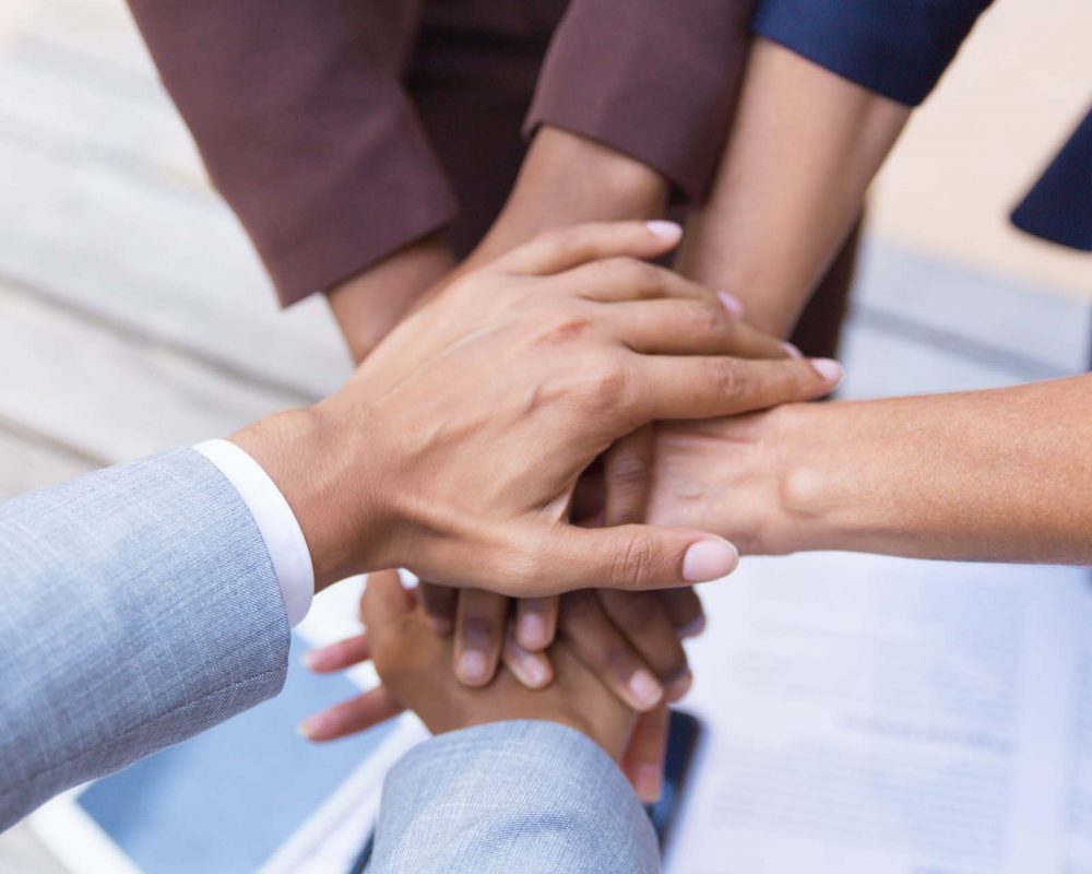 Business team putting their hands together, expressing unity, support, friendship. Closeup of people stacking hands. Teamwork and success concept